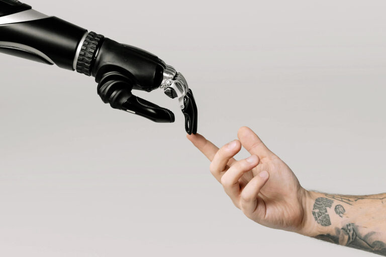 Photograph re-creation of "The Creation of Adam"; human hand reaches out to touch robotic arm.