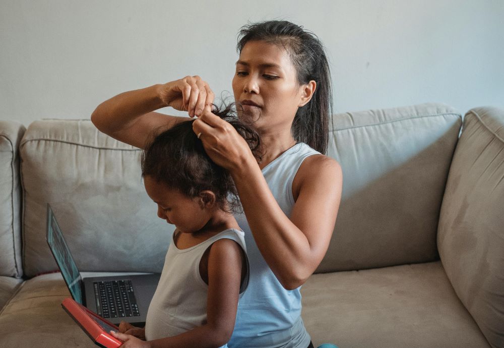 Woman prepares a girl's hair. 