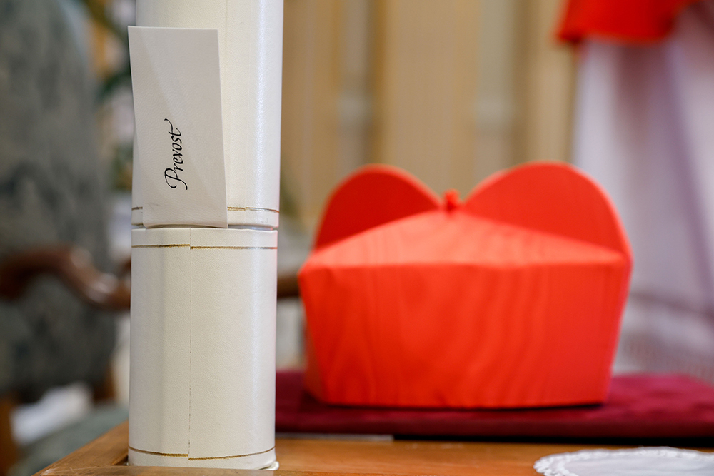 Chicago-born Cardinal Robert Prevost's red biretta and scroll, are seen next to his chair as he greets well-wishers in the Apostolic Palace at the Vatican after a consistory where Pope Francis made him and 20 other prelates cardinals Sept. 30, 2023. (CNS/Lola Gomez)