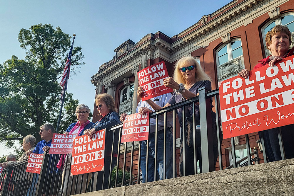 Anti-abortion demonstrators, holding signs and wearing red, pray the rosary outside the Missouri Supreme Court Building in Jefferson City the morning of Sept. 10, 2024. The high court ruled later that afternoon that Amendment 3, which would undo the state's near total-abortion ban and other related abortion restrictions, would be on the ballot Nov. 5 before voters. (OSV News/The Catholic Missourian/Jay Nies)