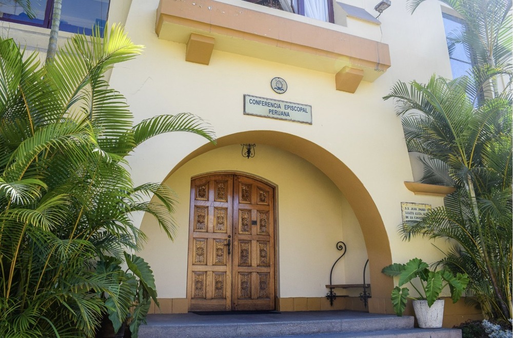 Facade of stucco building, graced by palms.