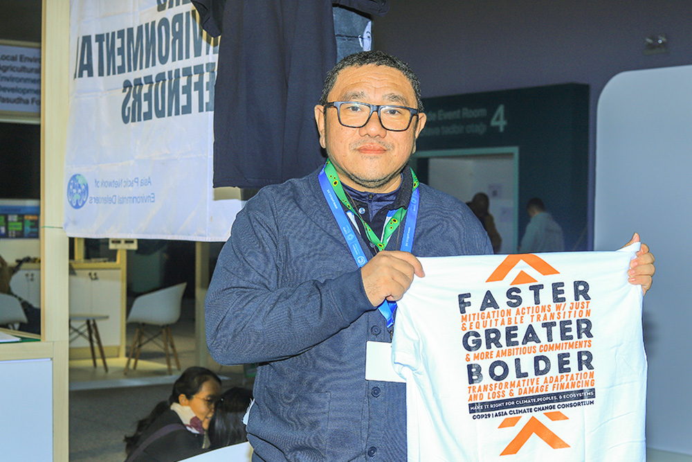 Rodne Rodiño Galicha, executive director of Living Laudato Si' Philippines, holds a T-shirt displaying a climate change message at COP29, the United Nations climate conference in Baku, Azferbaijan. (NCR photo/Doreen Ajiambo)