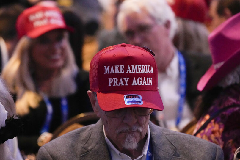 Man's head bowed, text of hat visible. 