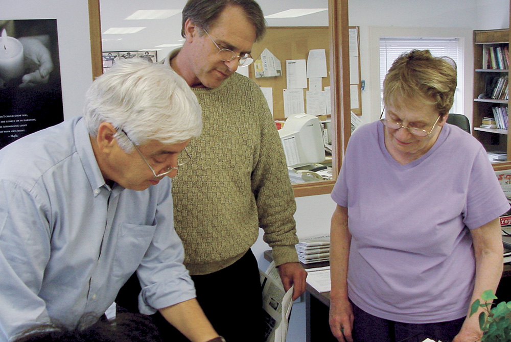 From left, NCR editor Tom Roberts, publisher Tom Fox and copy editor Patty McCarty review pages before sending them to the printer in 2004. (NCR photo/Toni-Ann Ortiz)