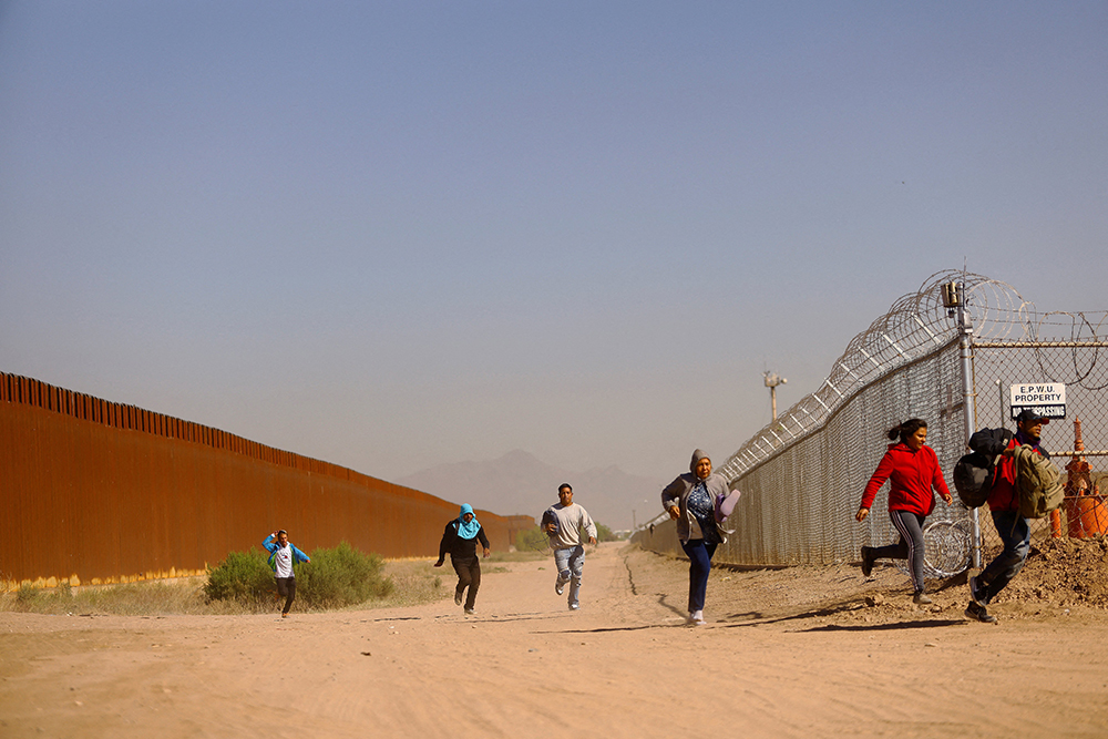 Migrants run to hide from the U.S. Border Patrol and the Texas National Guard in El Paso, Texas, May 8, 2023, after crossing into the United States from Mexico. (OSV News/Reuters/Jose Luis Gonzalez)