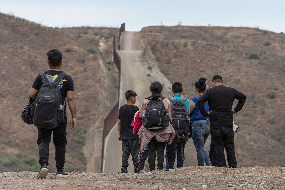 The Border Wall is seen in the background as migrants from South and Central America look to surrender to immigration officials after crossing into the United States from Mexico in Ruby, Ariz. June 24, 2024. (OSV News/Reuters/Adrees Latif)