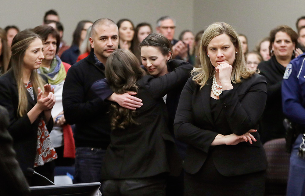 Former gymnast Rachael Denhollander, center, is hugged after giving her victim impact statement during the seventh day of Larry Nassar's sentencing hearing Jan. 24, 2018, in Lansing, Mich. (AP/Carlos Osorio)