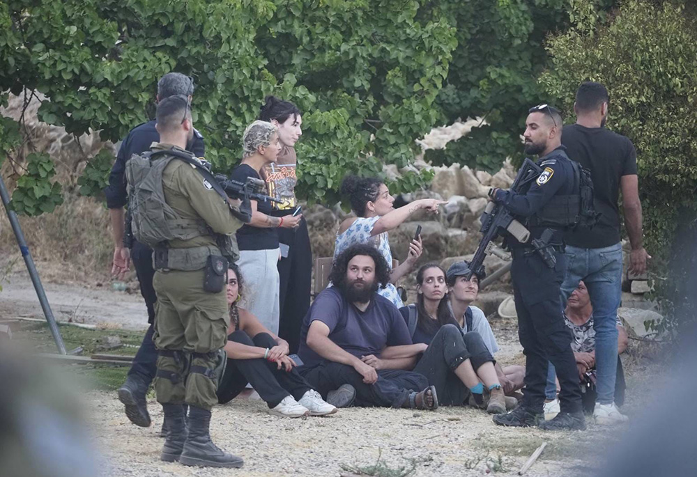 Amira Musallam, center, is surrounded by peacemakers protecting her on July 31 as she confronts representatives of the Israeli Defense Force, local police and Jewish settlers after the takeover of the home of her in-laws. (Courtesy of Amira Musallam)