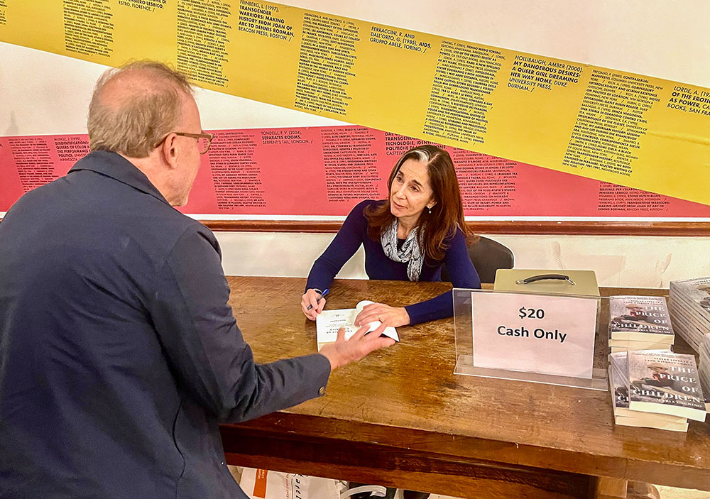 Maria Laurino signs a copy of her newly released book, The Price of Children, for an American adoptee who had just told her he knew about his condition thanks to her work, on Oct. 28 in New York. (NCR photo/Camillo Barone)