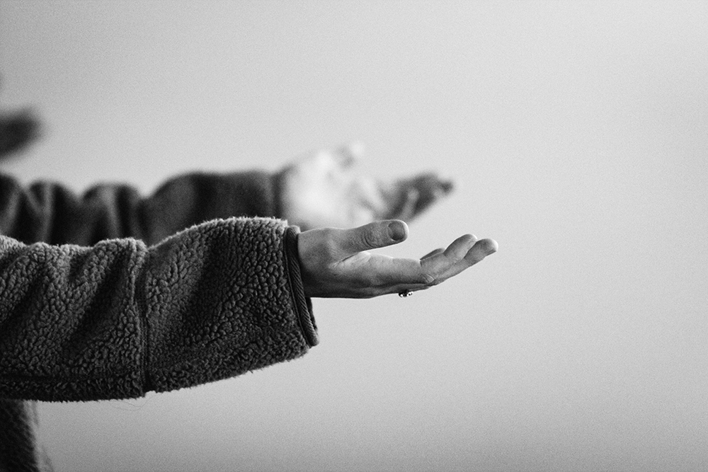 A black and white photo of someone holding up their hands, palms up (Unsplash/Jon Tyson)