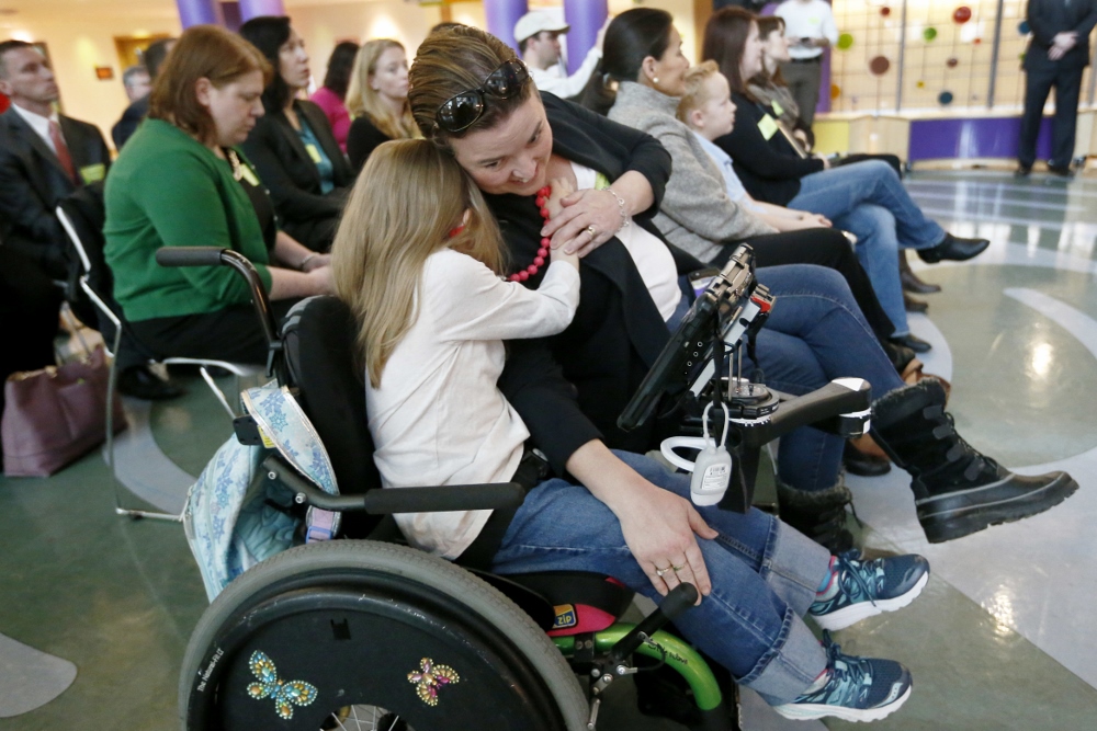 Eight-year-old Abigail Gabriel, center, hugs her mother, Erin, as Pennsylvania Department of Human Services Acting Secretary Teresa Miller talks about the Children's Health Insurance Program, CHIP, on Dec. 7, 2017, in Pittsburgh. (AP Photo/Keith Srakocic)