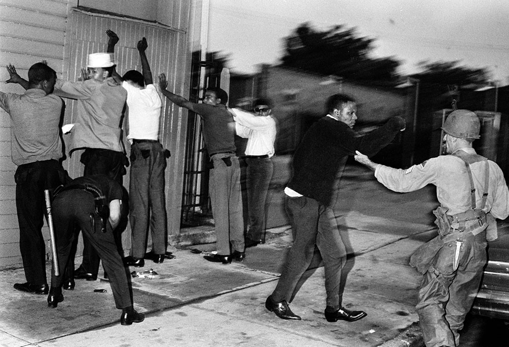 In this historical photo, a National Guardsman moves a Black man toward a wall as police search others in Newark, New Jersey, on July 15, 1967, during the Newark Rebellion. (AP Photo)