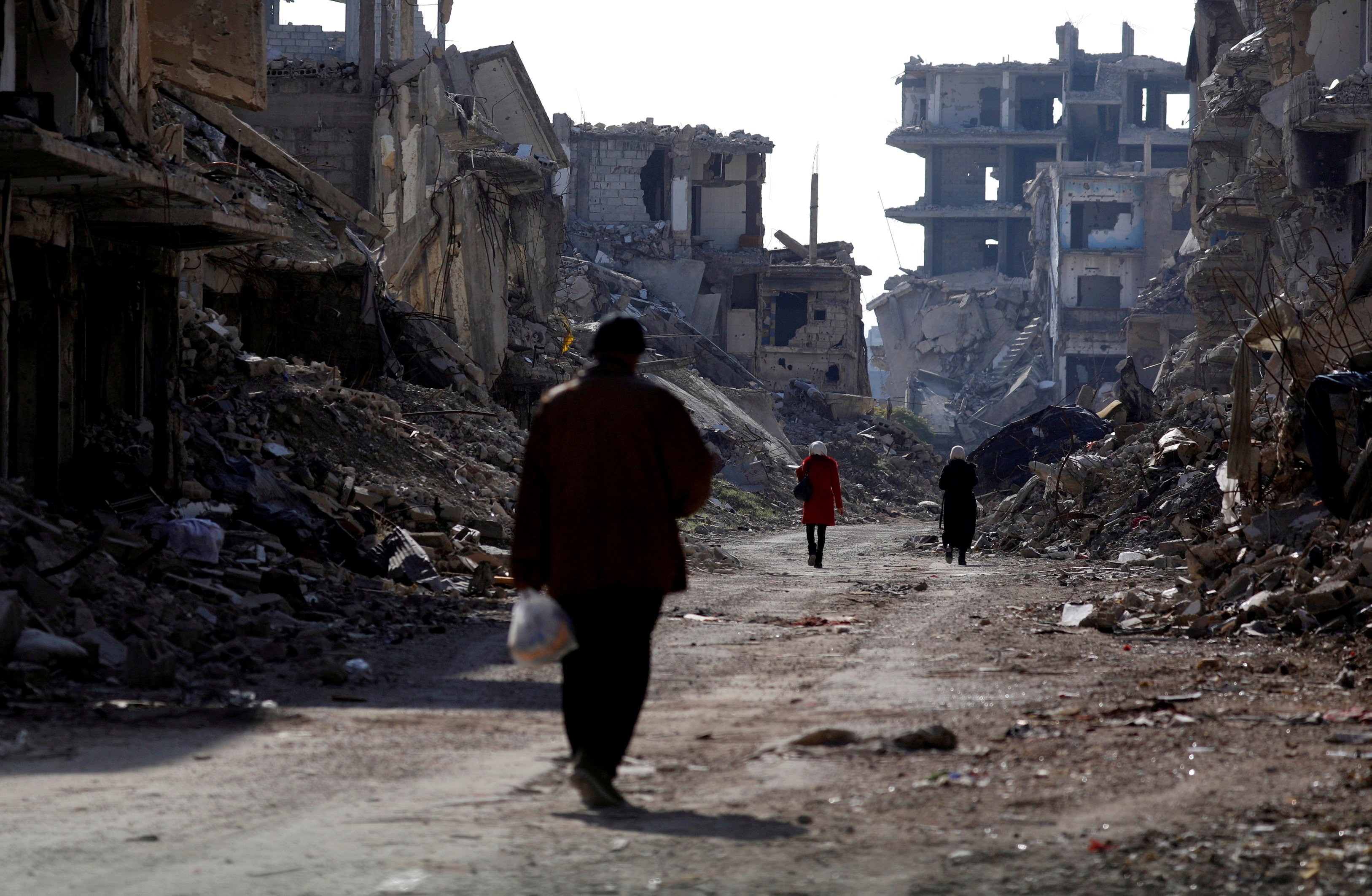 People walk past damaged buildings at the Yarmouk Palestinian refugee camp on the outskirts of Damascus, Syria Dec. 2, 2020.(CNS/Reuters/Omar Sanadiki)