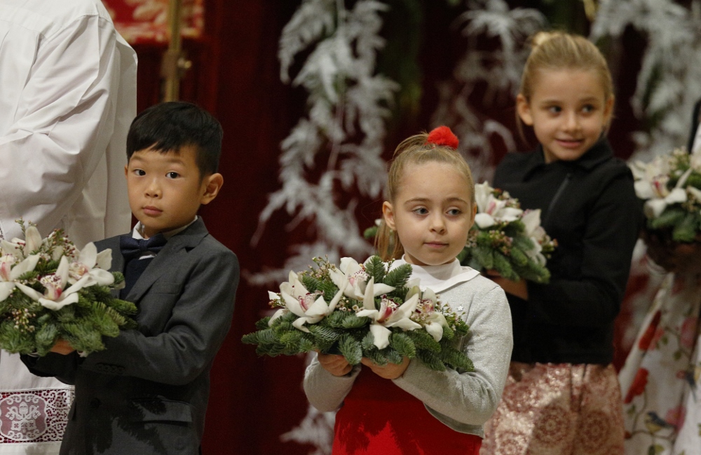 Children carry flowers to place at a figurine of the baby Jesus as Pope Francis celebrates Christmas Eve Mass in St. Peter's Basilica at the Vatican Dec. 24, 2017. (CNS/Paul Haring) 