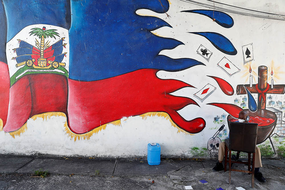 A man speaks on a phone next to a mural in the Little Haiti neighborhood of Miami July 8. (Newscom/Reuters/Shannon Stapleton)