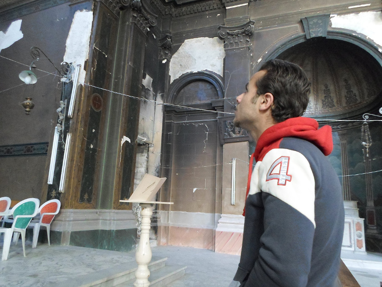 Istafanos Youssif, a university student from the port city of Suez, Egypt, stands inside the damaged Immaculate Conception Catholic Church in Suez Feb. 28. (CNS/James Martone) 