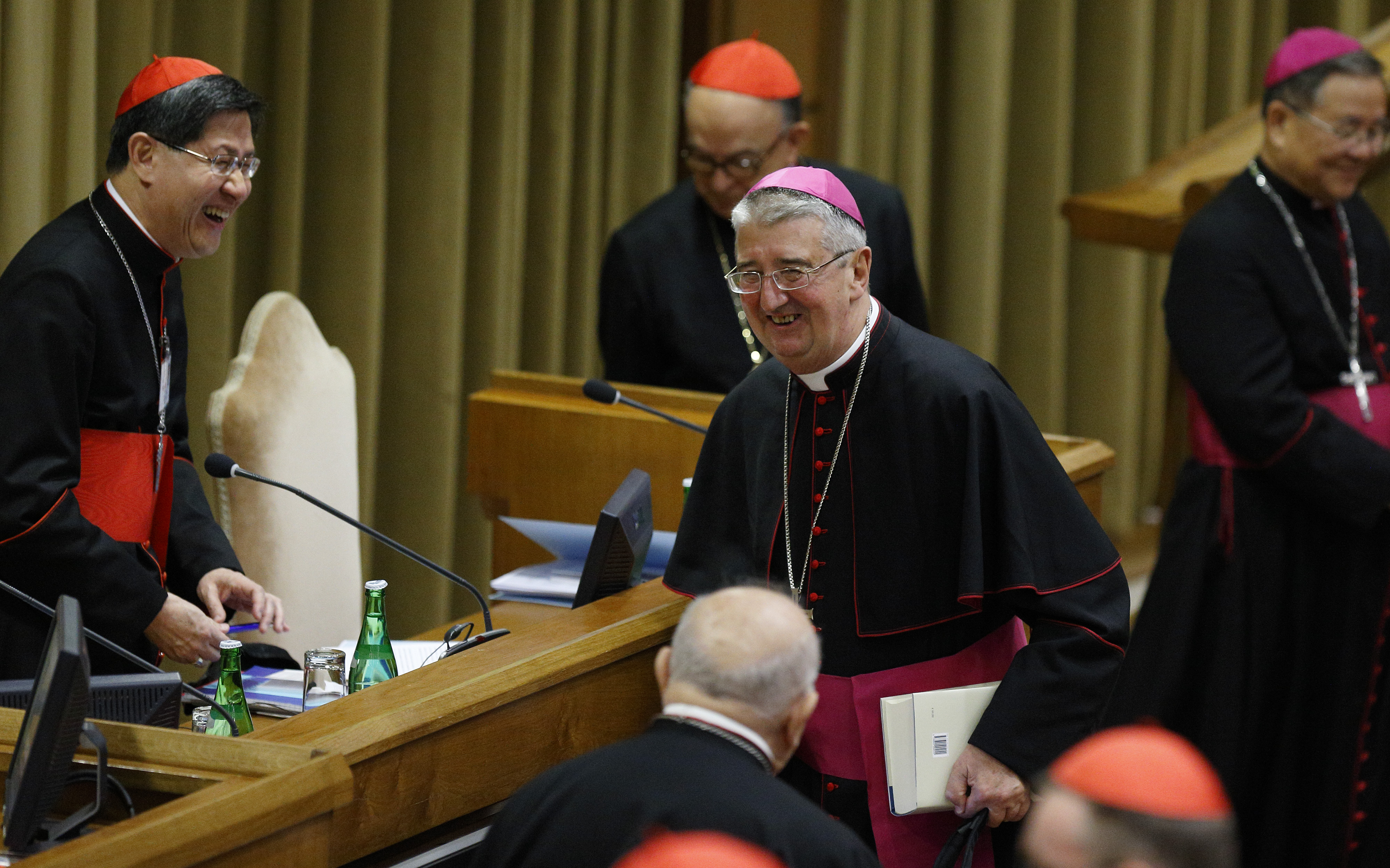 Irish Archbishop Diarmuid Martin of Dublin, center, shares a laugh with Cardinal Luis Antonio Tagle of Manila, Philippines, before the morning session of the extraordinary Synod of Bishops on the family at the Vatican Oct. 9. (CNS/Paul Haring)