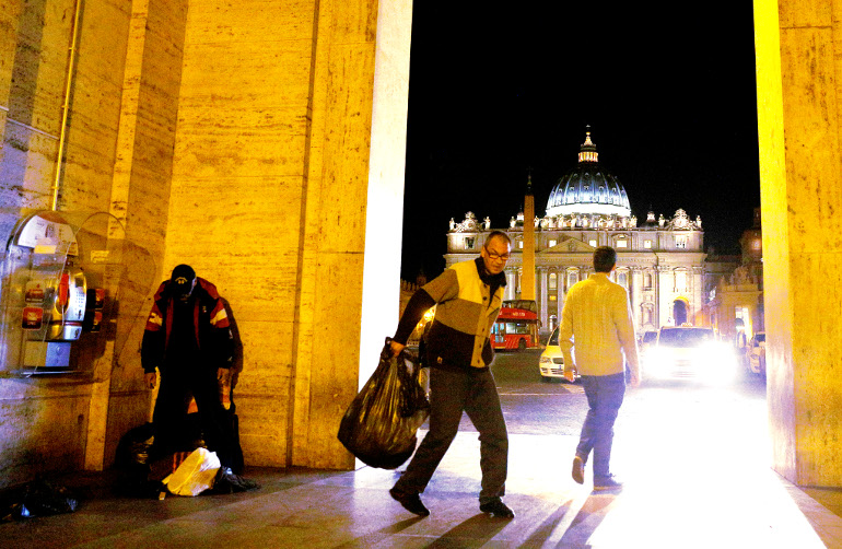 A homeless man carries possessions in a trash bag as another, left, stands outside the Vatican press office near St. Peter's Square Nov. 13, 2014. (CNS/Paul Haring)