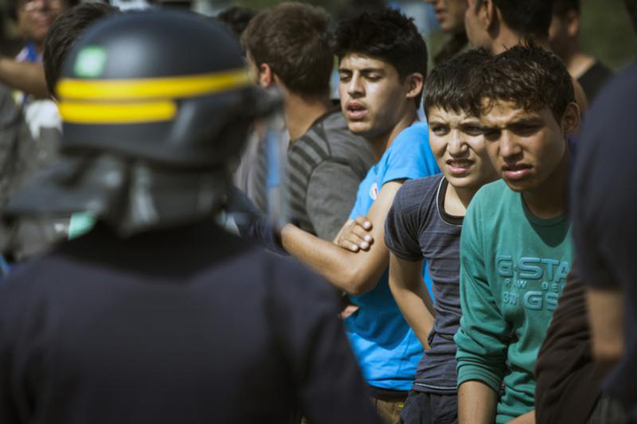 French police face migrants next to the "Jungle" migrant camp and try to prevent them from jumping on trucks near Calais, France, Aug. 5. Catholic bishops from France and Britain have urged their governments to settle a growing refugee crisis around the port of Calais, where highways have been blocked and migrants from Africa and the Middle East have died attempting illegal crossings of the Channel Tunnel. (CNS photo/Etienne Laurent, EPA) 