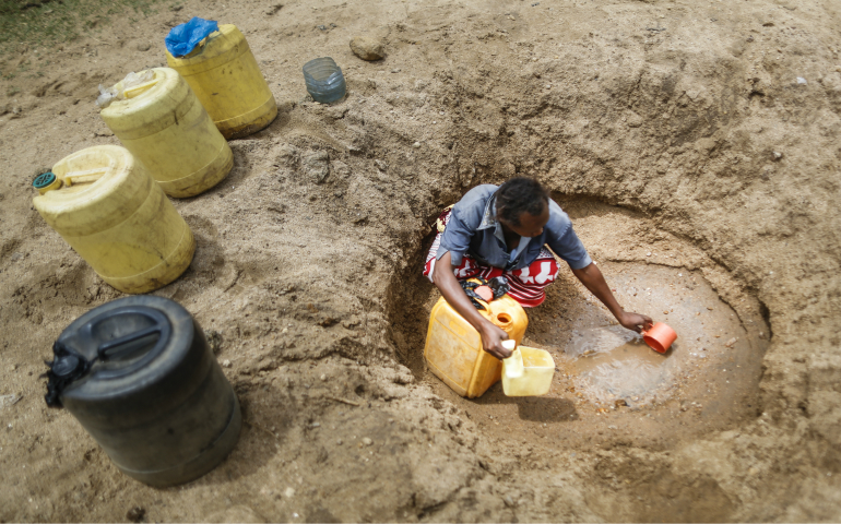 A woman scoops water in 2015 from a hand-dug well in a dry riverbed near Matinyani, Kenya. Kenya's Catholic bishops are appealing to the international community for relief food because of a recent drought. (CNS photo/Dai Kurokawa, EPA)