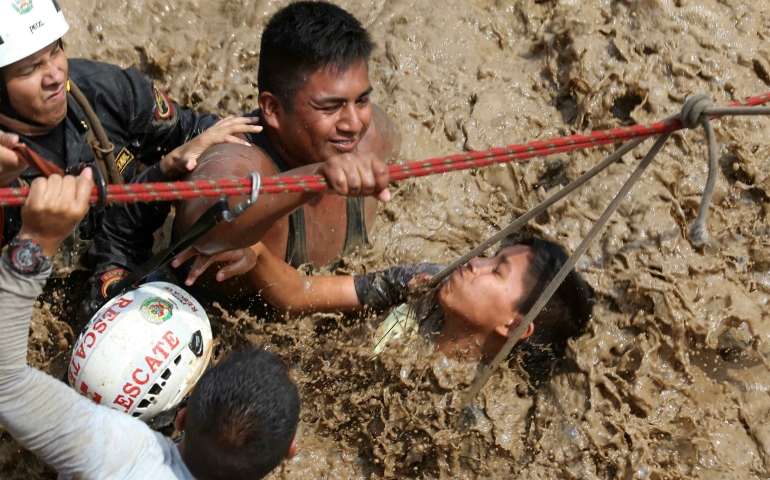 Agents of the Peruvian National Police rescue people from floodwaters March 17 near the Rimac and Huaycoloro rivers in Lima. (CNS photo/Ernesto Arias, EPA)