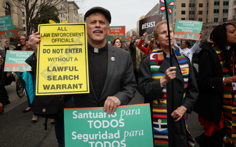 Rev. Charles Booker holds signs at the launch of a D.C.-Maryland-Virginia regional network of sanctuary congregations in Washington, D.C., March 21, at Foundry United Methodist Church. (NCR photo/Rick Reinhard)