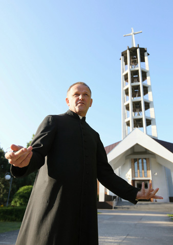 Fr. Wojciech Lemanski stands in front of his former parish in Jasienica, Poland, on July 16.