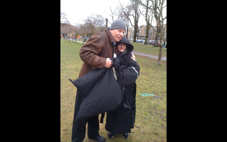 A volunteer presents a young woman with a comfort coat. (Helpers of St. Anne and St. Joachim)