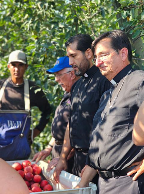 From right, Bishop Joseph Tyson, Fr. Jesús Mariscal and Fr. Richard Notter meet farmworkers Aug. 28 during an annual pastoral visit to migrants by representatives of the Catholic Migrant Farmworker Network and the U.S. bishops' Subcommittee on the Pastoral Care of Migrants, Refugees and Travelers. (Diocese of Yakima/Ana Contreras)