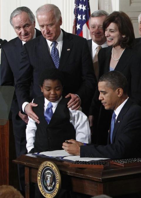 Then-Vice President Joe Biden watches as U.S. President Barack Obama signs health care legislation. 