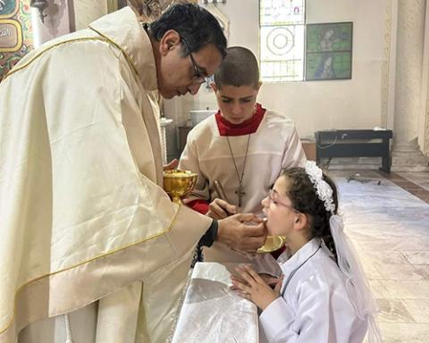 On Jan. 7, 2024, the feast of Epiphany, Fr. Youssef Asaad, an assistant priest at the Holy Family Parish in Gaza City, administers the sacrament of first Communion to one of eight children of the parish after they completed their preparation program and education, despite the ongoing Israel-Hamas war. (OSV News/Courtesy of Latin Patriarchate of Jerusalem)