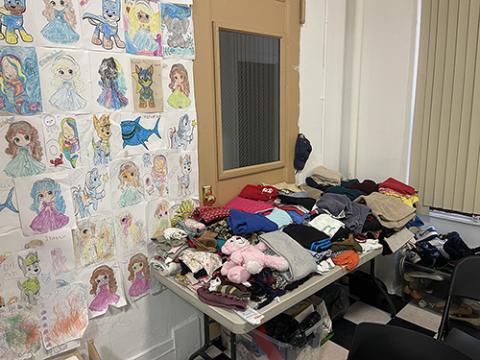 A desk with clothes and toys is pictured at the reception center for incoming immigrants at St. Teresa's Church, in Manhattan’s Lower East Side, December 2024. (Camillo Barone)