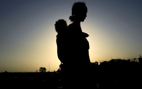 An Ethiopian woman carries her child as she flees the ongoing fighting in the Tigray region near the Setit River on the Sudan-Ethiopia border Nov. 22, 2020. (CNS/Reuters/Mohamed Nureldin Abdallah)