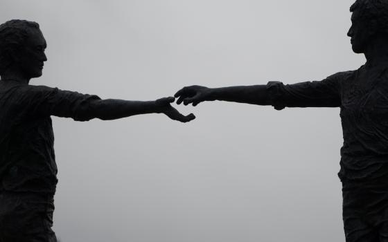 A silhouette of the statue Hands Across the Divide is pictured in Londonderry, Northern Ireland. The bronze was unveiled in 1992, 20 years after Bloody Sunday, when British troops killed 14 Catholic demonstrators. (CNS/Reuters/Clodagh Kilcoyne)