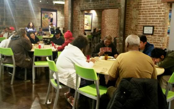 People enjoy dinner at Bishop Sullivan Center's One City Café, a restaurant-style community kitchen offering free meals in Kansas City, Missouri, as volunteers and staff serve them Feb. 26. (NCR photo/Maria Benevento)