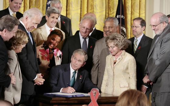 President George W. Bush signs a bill that extends the President’s Emergency Program for AIDS Relief, known as PEPFAR, surrounded by lawmakers and other supporters of the program at the White House in Washington July 30, 2008. (CNS/Reuters/Larry Downing)