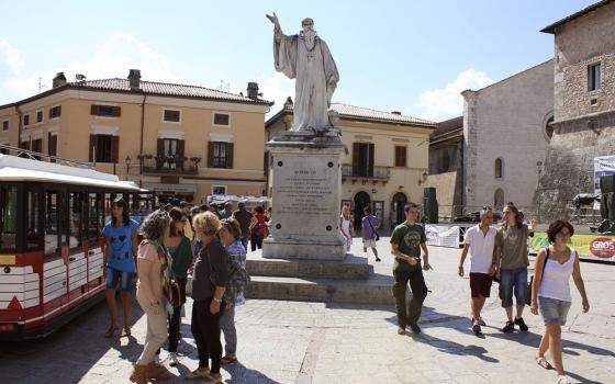 Tourists and townspeople surround a statue of St. Benedict Aug. 14, 2013, in the small Italian town of Norcia. (CNS/Henry Daggett)