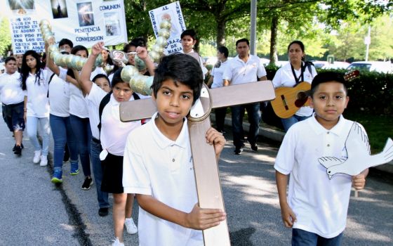 Jesus Solorio, 11, carries a cross during a Eucharistic Congress procession June 17, 2017, in College Park, Ga., in the Atlanta Archdiocese. He is a parishioner of St. Thomas Aquinas Church in Alpharetta, Ga. (CNS/Georgia Bulletin/Michael Alexander)