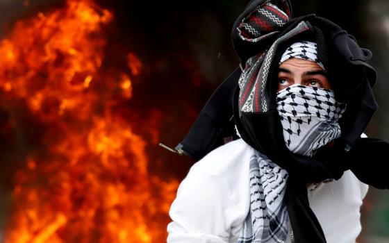 A Palestinian throws a stone at Israeli forces near Ramallah, West Bank, during a Dec. 20 protest against U.S. President Donald Trump's decision to recognize Jerusalem as the capital of Israel. (CNS/Reuters/Goran Tomasevic)