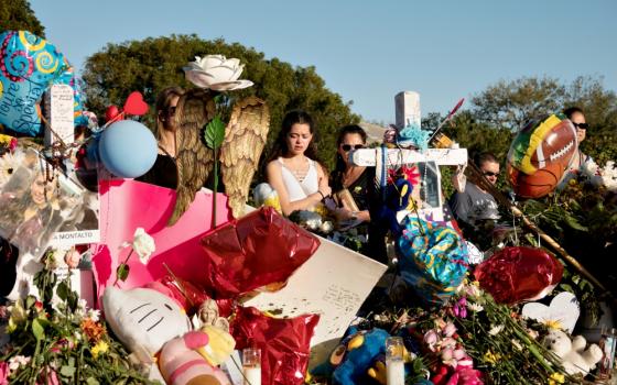 A young woman mourns in front of a memorial to mass shooting victims Feb. 25 at Marjory Stoneman Douglas High School in Parkland, Florida. (CNS/Reuters/Angel Valentin)