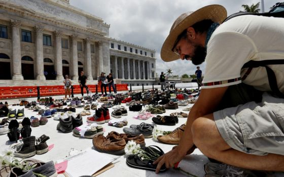 A man in San Juan, Puerto Rico, places a pair of sandals in front of the capitol building June 1 to represent those killed by Hurricane Maria. (CNS/EPA/Thais Llorca)