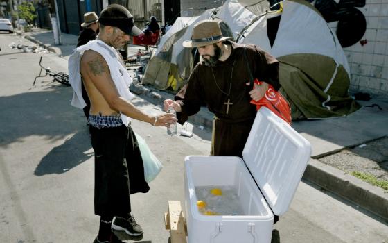 Brazilian Friar Benjamin of the Most Holy Trinity gives water to a man on Skid Row in Los Angeles Aug. 18. (CNS/John McCoy via Angelus News)