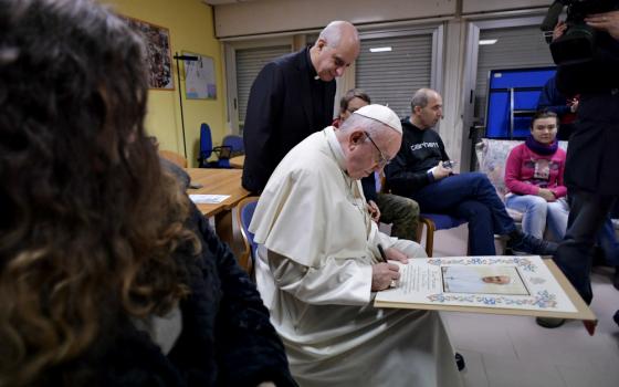 Pope Francis signs a papal blessing as he visits mentally disabled people at Il Ponte e l'Albero community on the outskirts of Rome Dec. 7, 2018. (CNS/Vatican Media) 