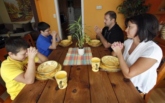 A family prays together before a meal in 2012 at their Chicago home. (CNS photo/Karen Callaway, Catholic New World)