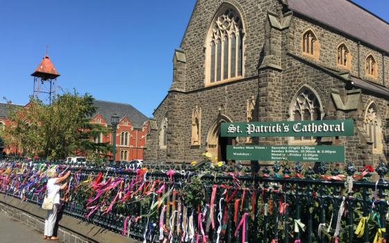 A woman puts a ribbon on the fence of St. Patrick's Cathedral in Ballarat, Australia, in February 2019. The ribbons raise awareness and show support for victims of abuse. (CNS/Reuters/Jonathan Barrett)