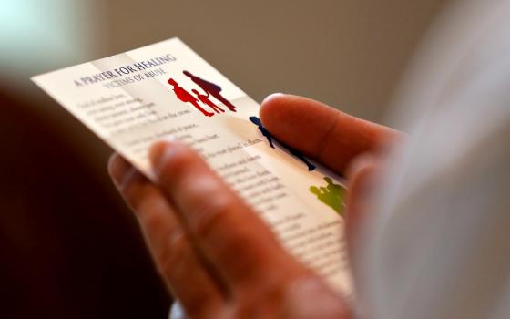 A clergyman reads a prayer card during a Mass with special intentions for survivors of abuse and for abuse prevention in the chapel of the headquarters of the U.S. Conference of Catholic Bishops in Washington April 8. (CNS/Bob Roller)