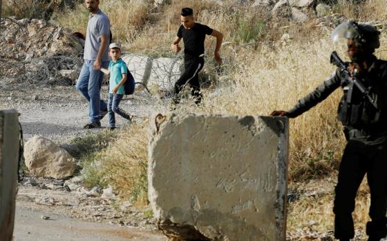 An Israeli border policeman stands guard not far from Ramallah, West Bank, May 17, 2019, as Palestinians make their way to attend Friday prayer at al-Aqsa mosque in Jerusalem's Old City. (CNS/Reuters/Raneen Sawafts)