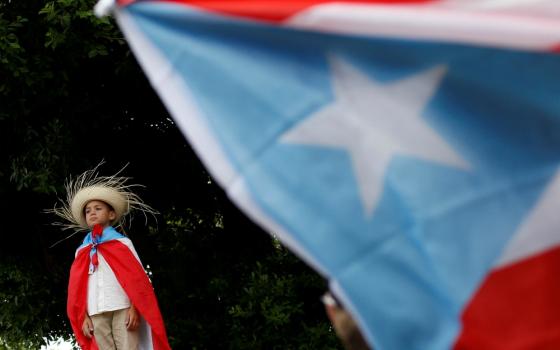 A youth draped in a Puerto Rican flag attends a rally to celebrate the resignation of Puerto Rican Gov. Ricardo Rosselló in San Juan July 25. (CNS/Reuters/Marco Bello)