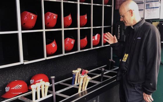 Msgr. Stephen Rossetti, a professor at the Catholic University of America and the chaplain for the Washington Nationals, blesses bats before a game during the 2019 season. (CNS/Courtesy of Msgr. Stephen J. Rossetti)