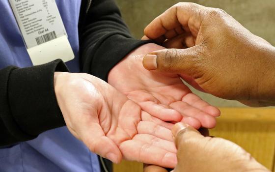 A personal care assistant has her hands anointed in a 2018 photo. (CNS/Gregory A. Shemitz)